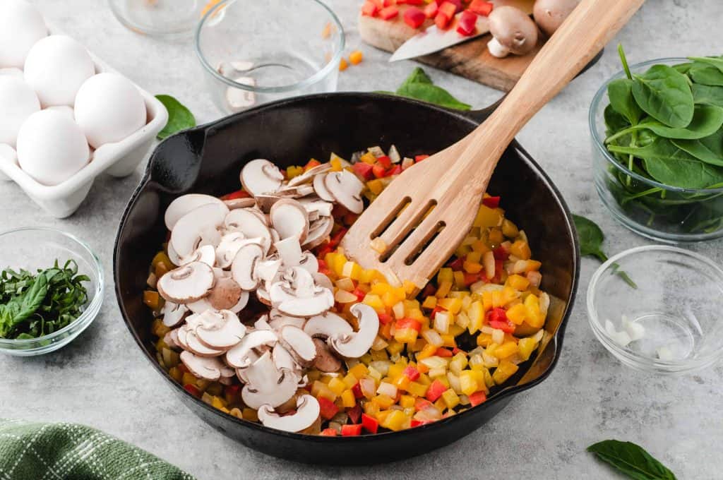 Sautéed bell peppers and mushrooms in a black iron skillet.