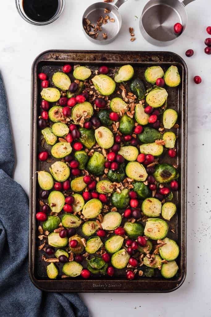 Cranberries and pecans on a sheet pan with Brussels sprouts.