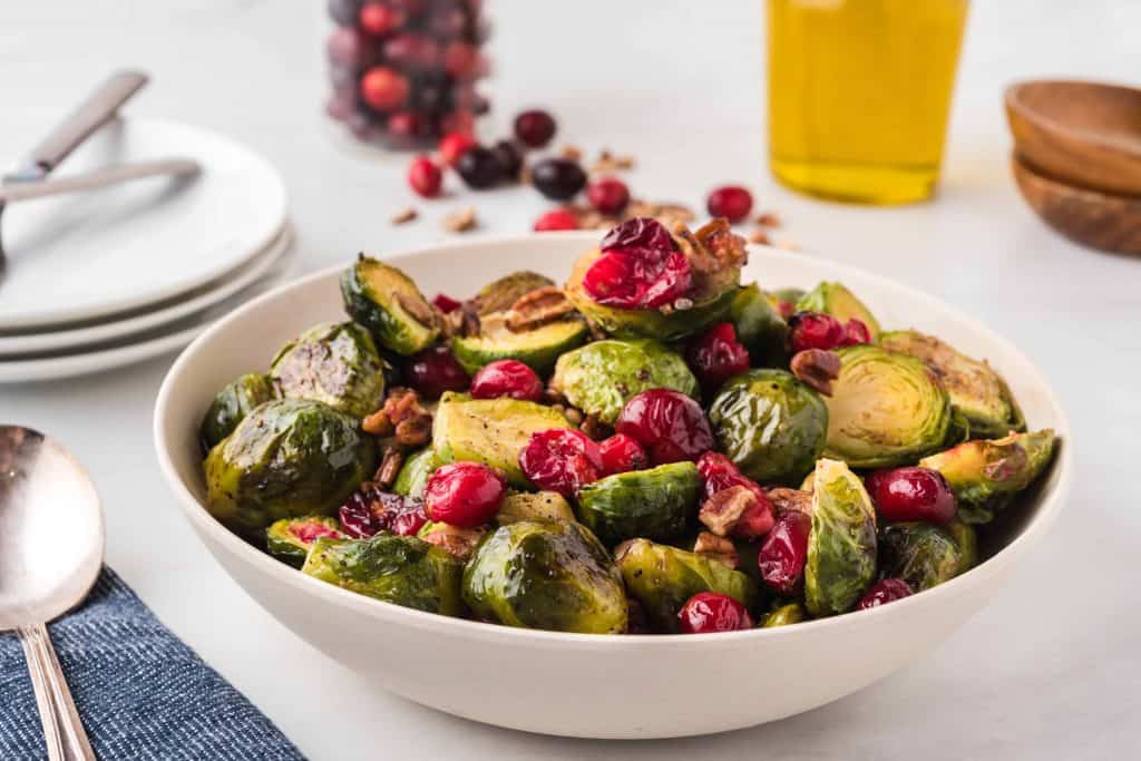 Roasted Brussels Sprouts and Cranberries with pecans in a white bowl.
