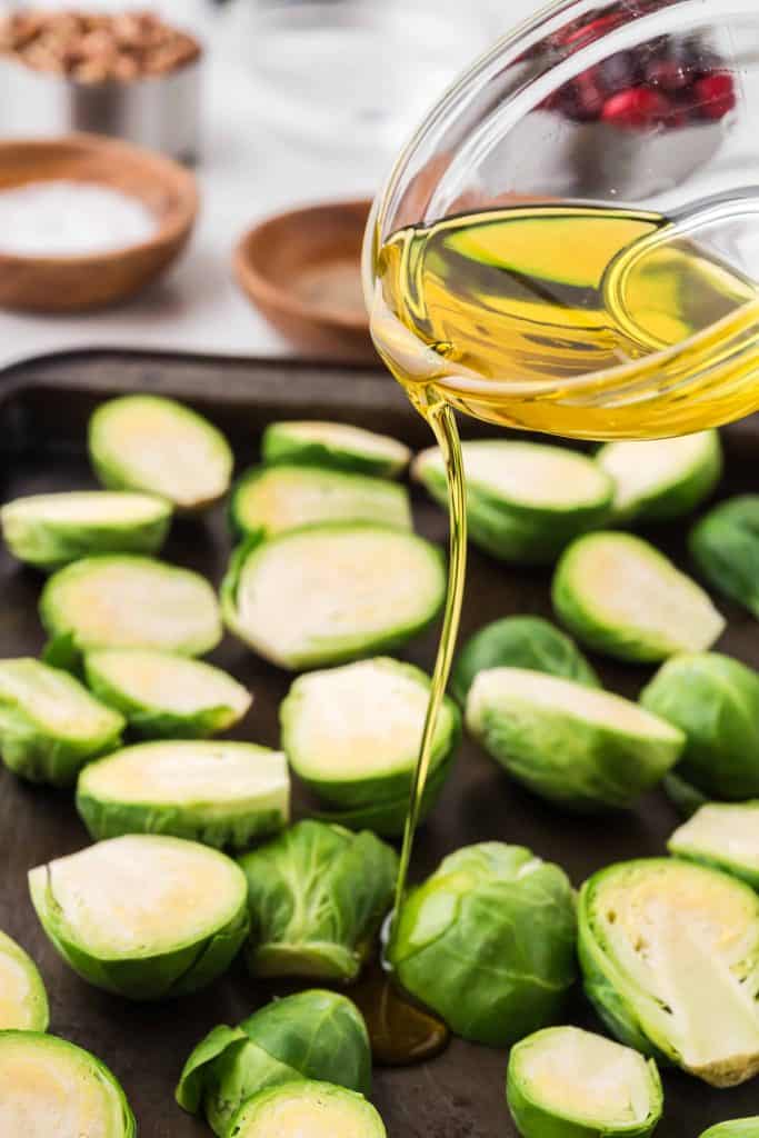 Olive oil being poured on top of Brussels sprouts