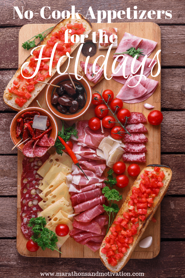 A charcuterie board with capitol, salami, pepperoni, and cured meats, also including black olives, cherry tomatoes, swiss cheese, and a baguette with diced roasted red peppers