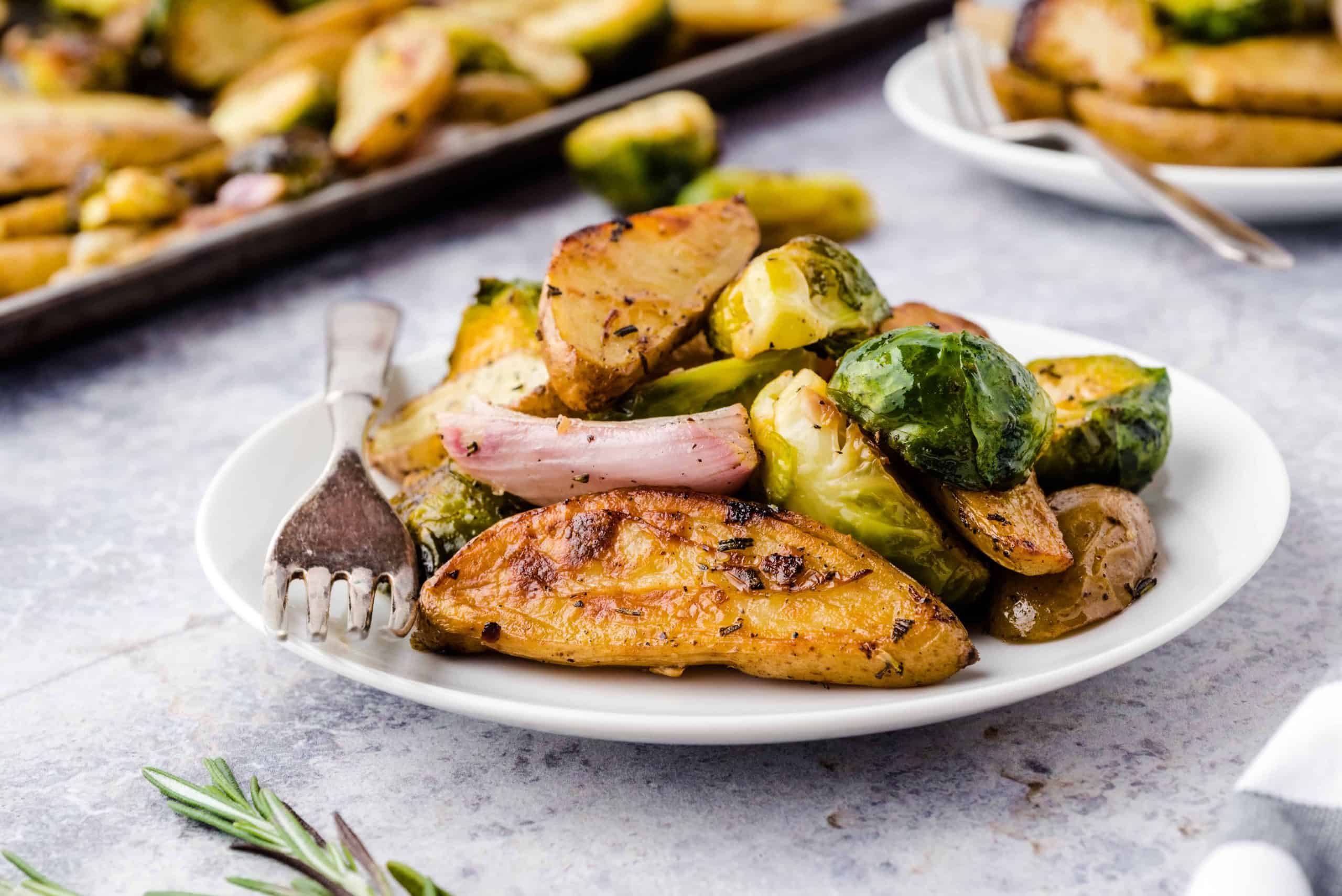 potatoes and sprouts and shallots on a white plate with a fork.