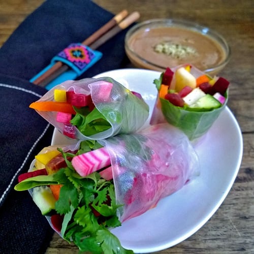 Beet spring rolls with almond sauce on a white plate
