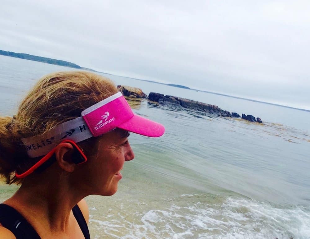 Woman by the ocean wearing headphones and visor