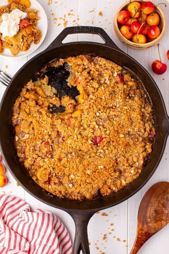 Rainier cherry crumble in a cast iron skillet topped with golden brown almond crumble