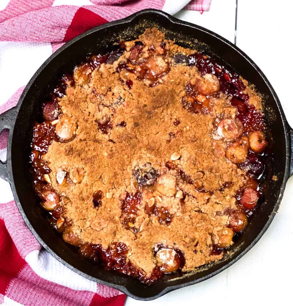 Overhead shot or Rainier Cherry Crumble in a black iron skillet.