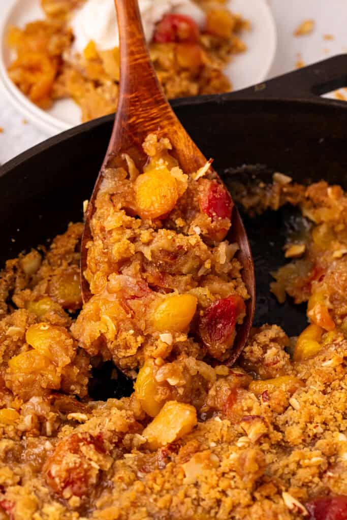 serving cherry crumble with a wooden spoon