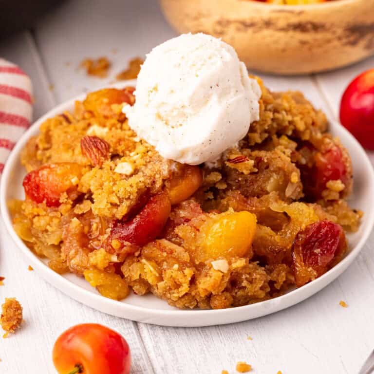 Cherry crumble with vanilla ice cream on a white plate