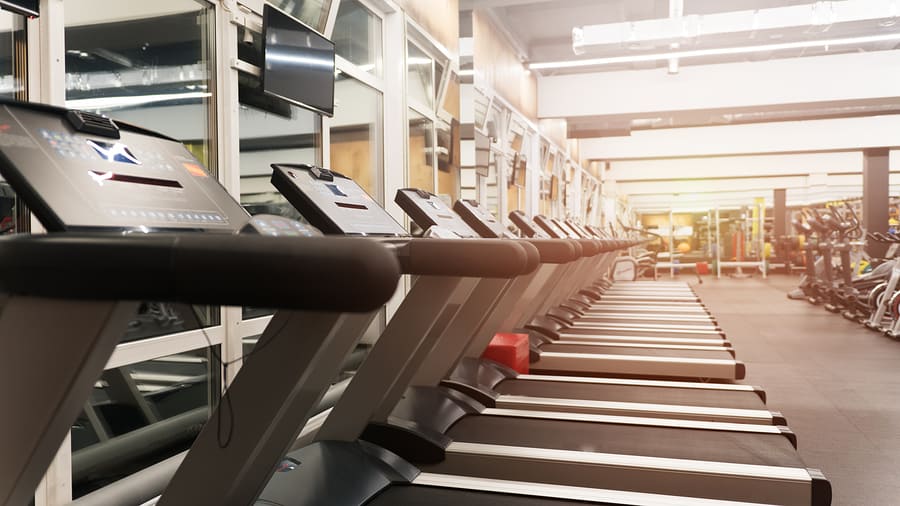 Fitness gym club with row of treadmills for fitness cardio training. Healthy lifestyle concept. Modern gym interior with equipment.