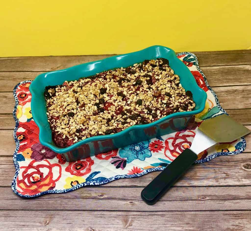 Granola berry crisp on a flowered placemat with a serving spatula