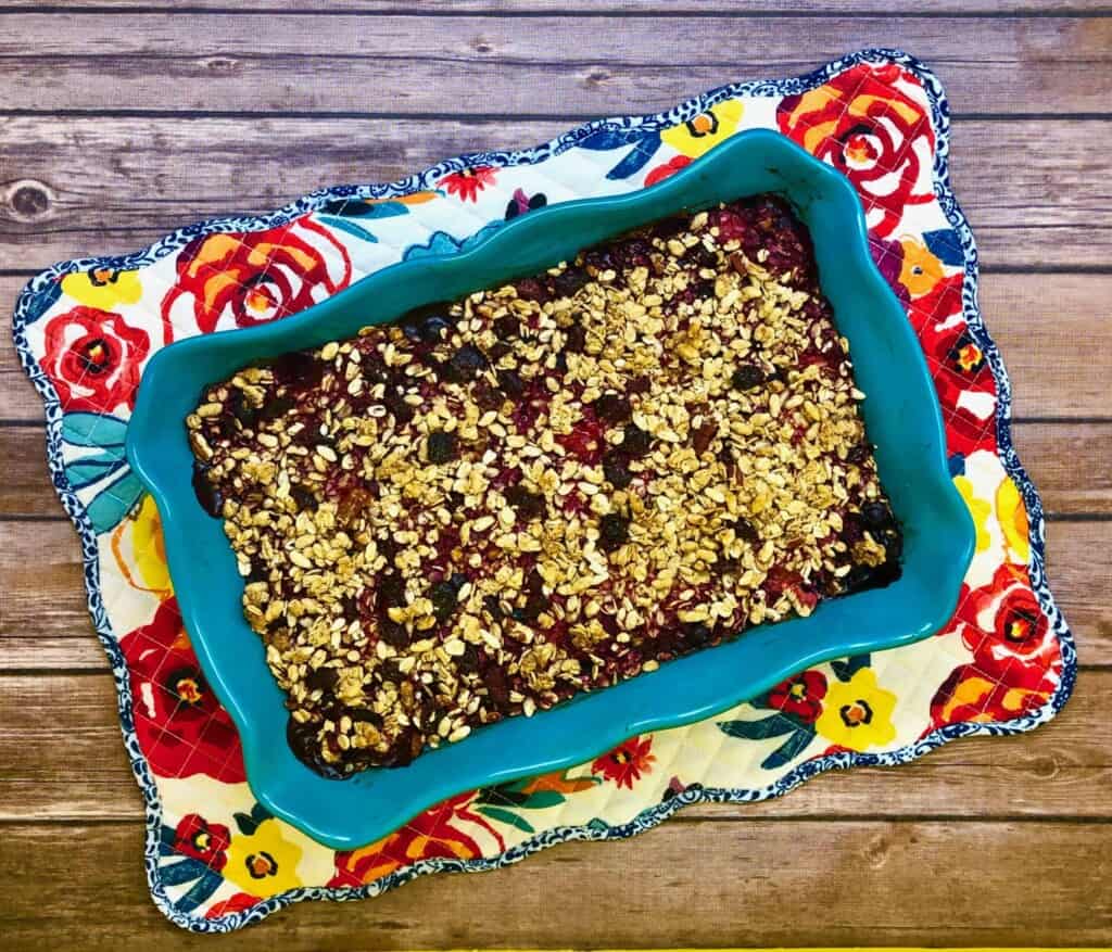 Berry Crisp in a casserole dish on a flowered placemat with a wood background.