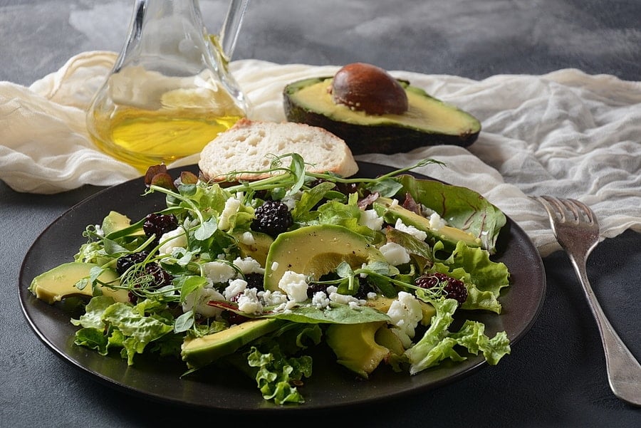 Health Benefits of Avocado Oil Avocado salad with lettuce, blackberry, blue cheese, olive oil and arugula on a plate. Healthy vegan food concept