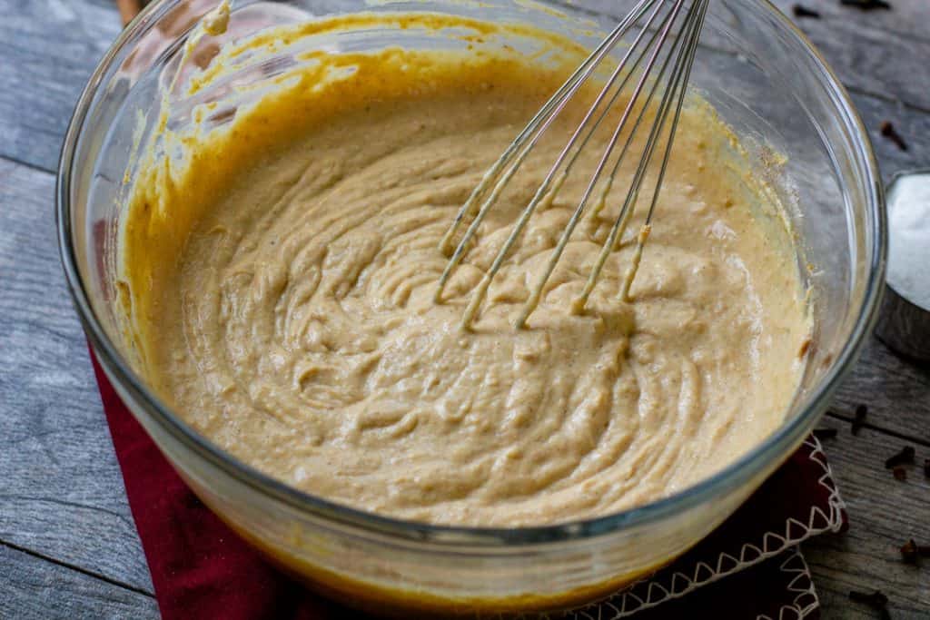 Pumpkin cheesecake bite ingredients whisked in a bowl on wood table