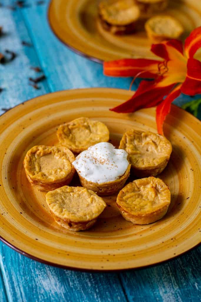 Healthy pumpkin cheesecake bites on an orange plate with a blue background