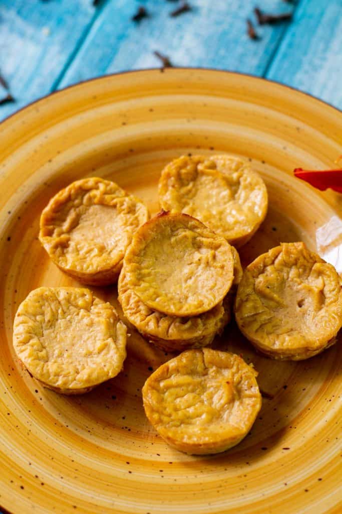 Healthy pumpkin cheesecake bites on an orange plate with a blue background