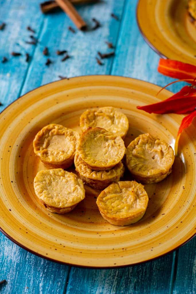 Healthy pumpkin cheesecake bites on an orange plate with a blue background