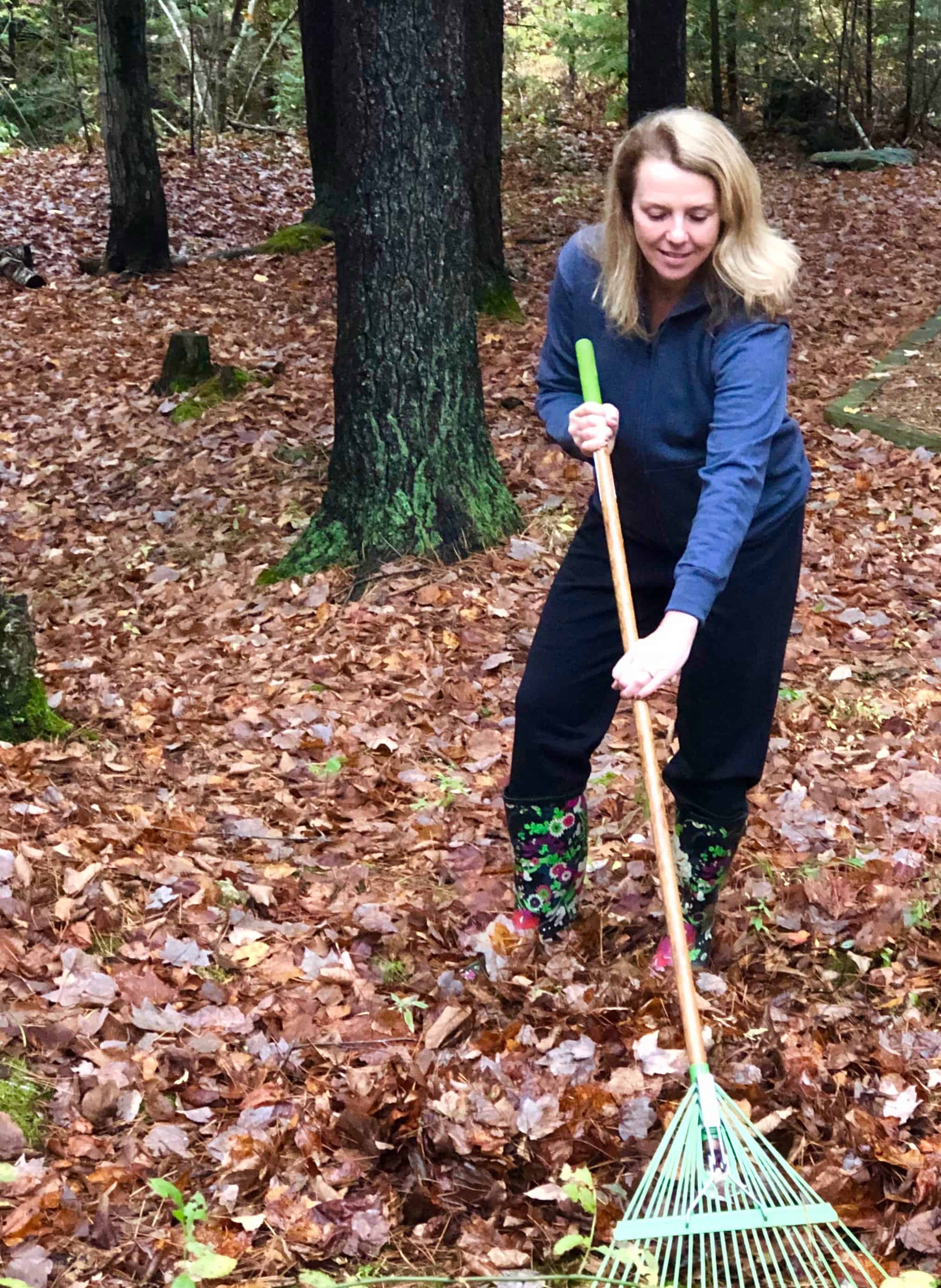 Beautiful blonde woman in sweatpants raking leaves in Maine.