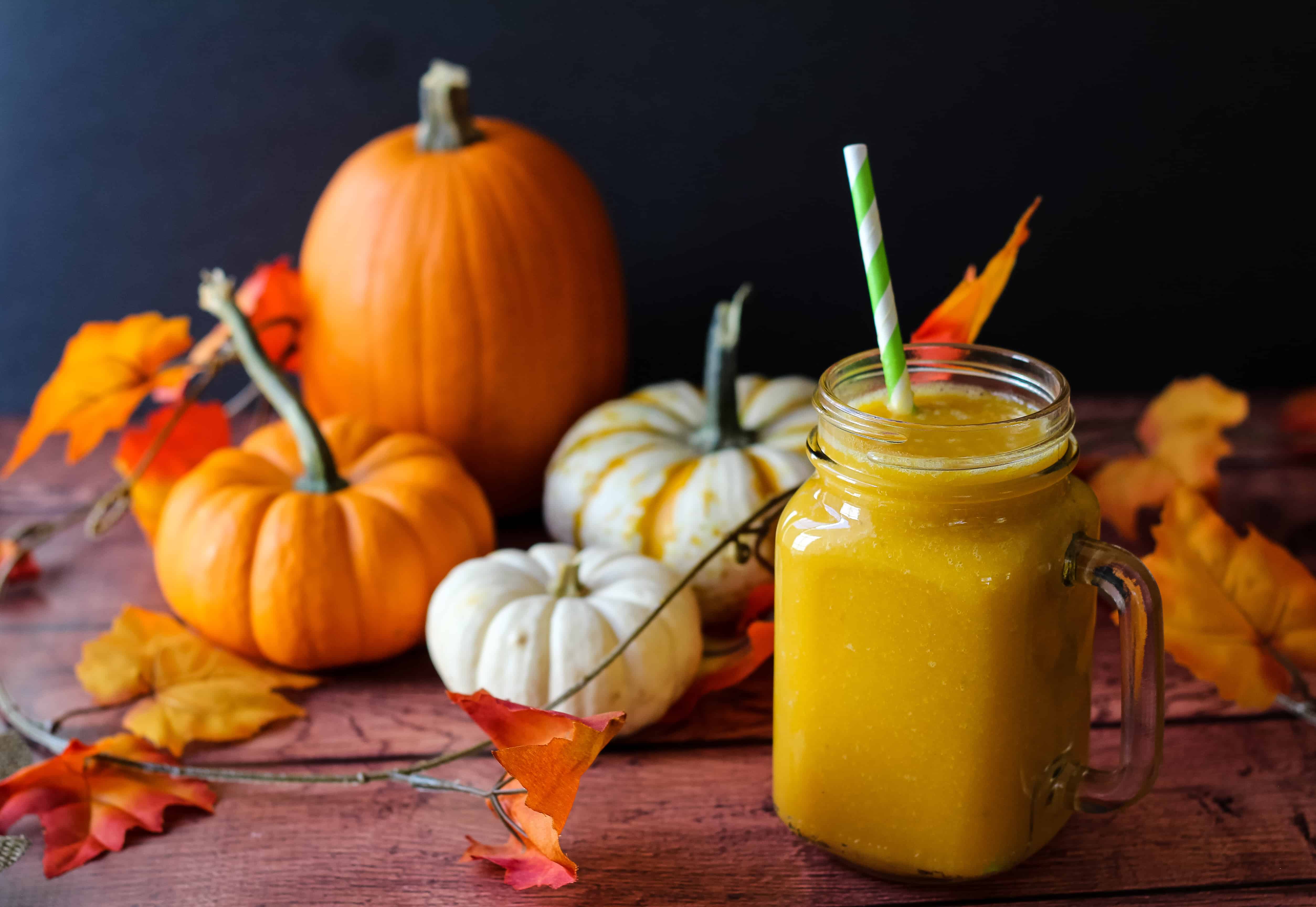 Healthy pumpkin smoothie with decorative pumpkins and leaves in the background