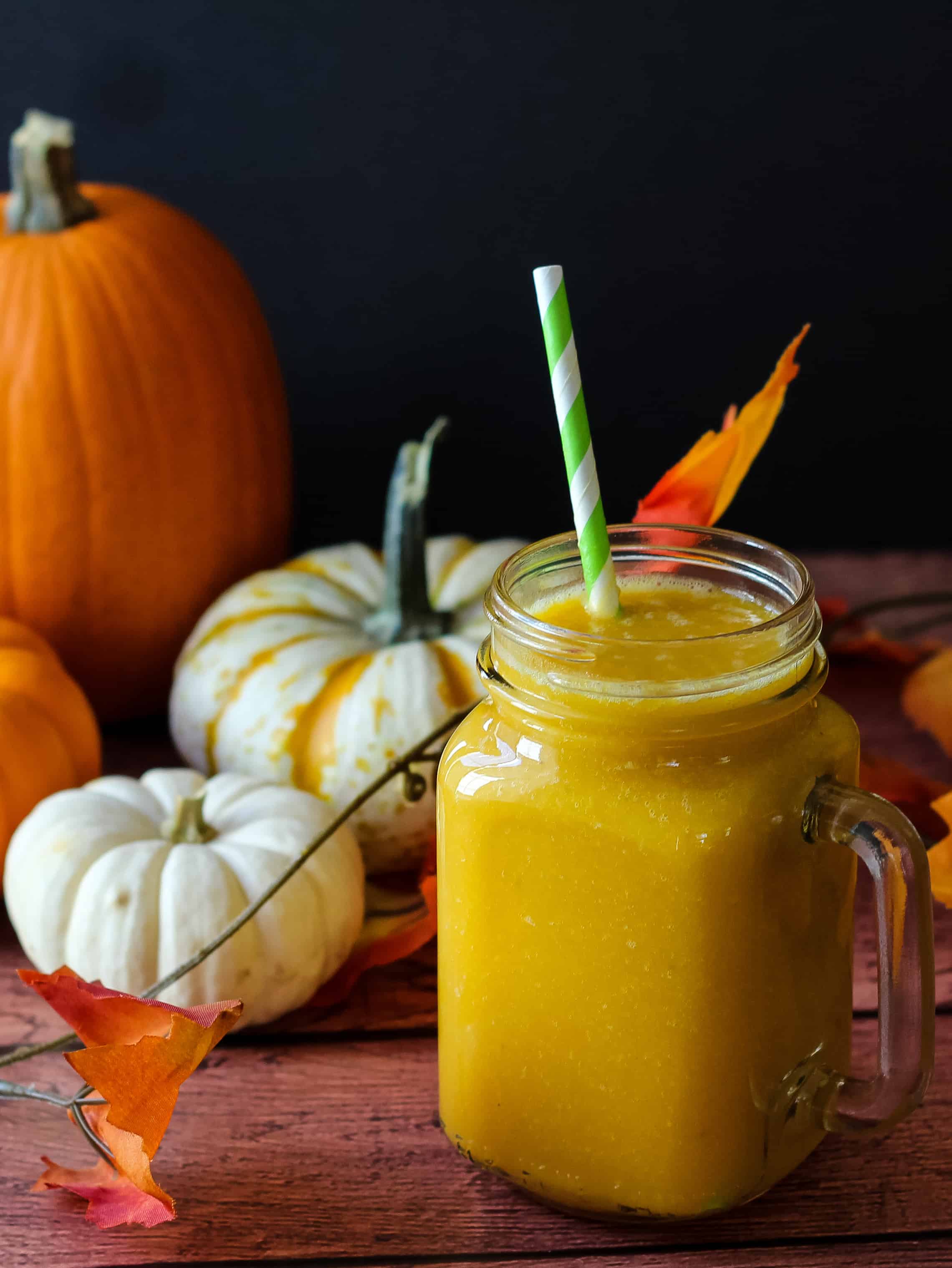 pumpkin smoothie with decorative pumpkins and leaves in background