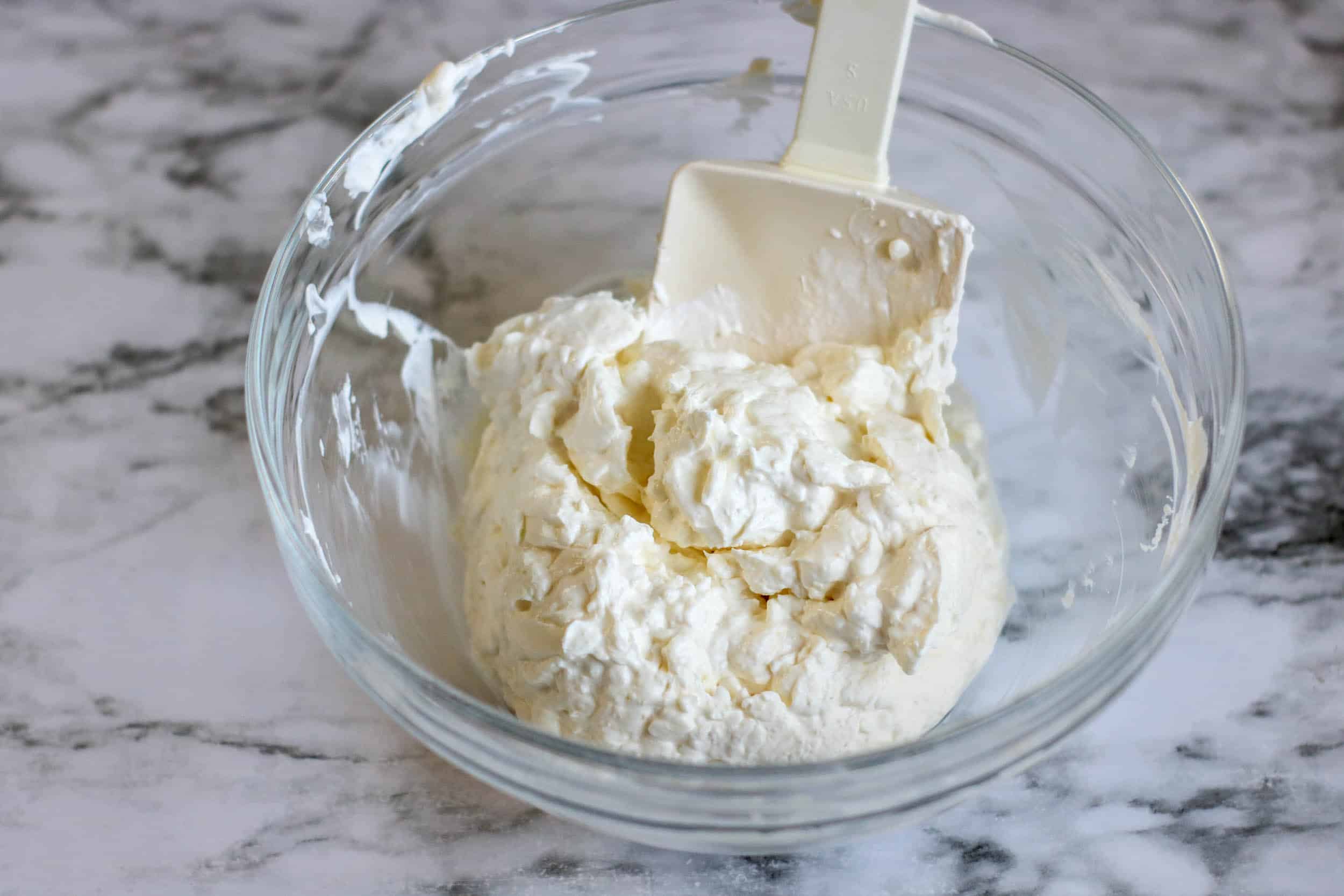 Cream cheese and sour cream in a glass bowl.