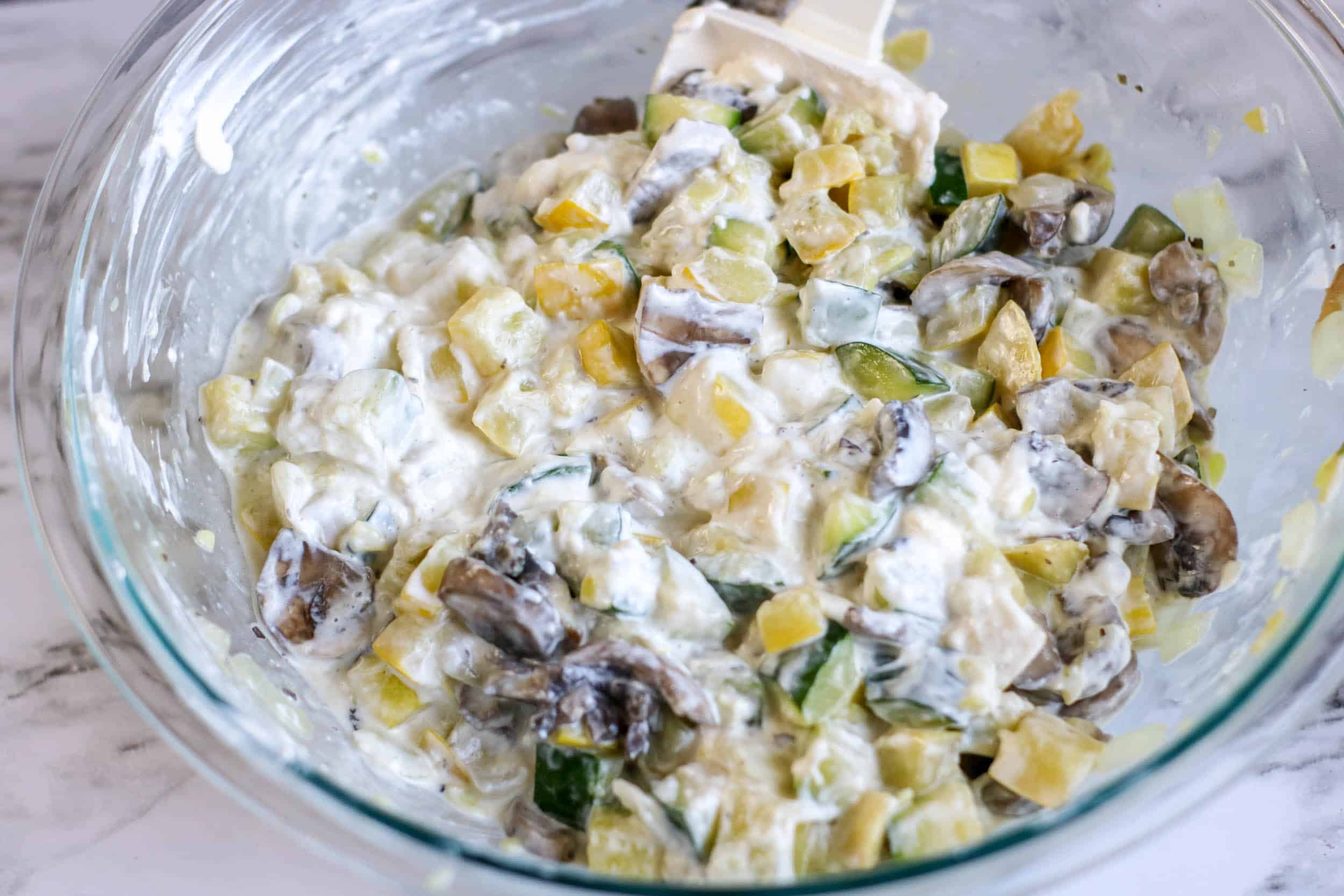 Chopped zucchini, squash, onion and mushrooms in a bowl with cream cheese and sour cream.