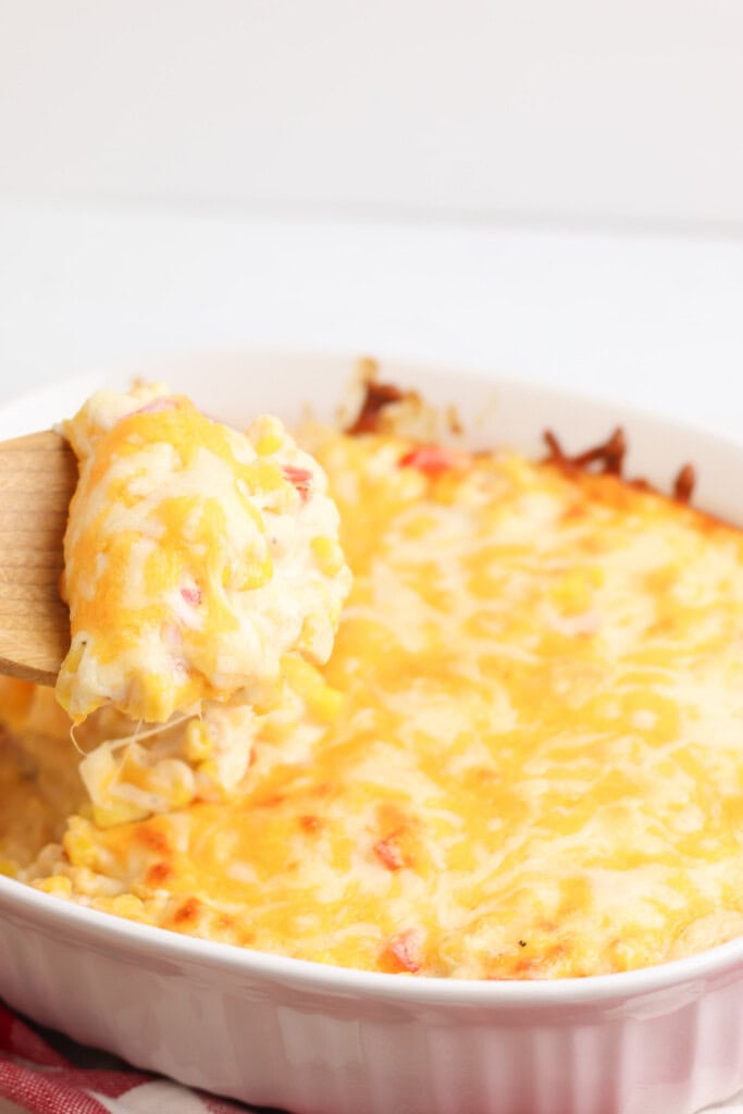 baked corn casserole with wooden sserving spoon in it