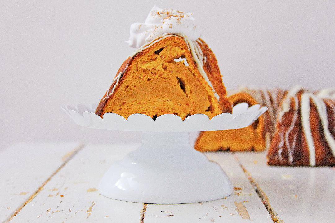 Pumpkin Angel Food Cake on a white cake stand with a white background.