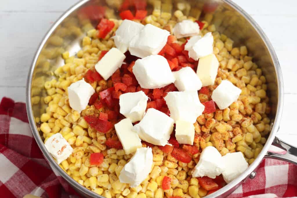 seasoned ed bell peppers corn and cream cheese cubes in a skillet.jpg