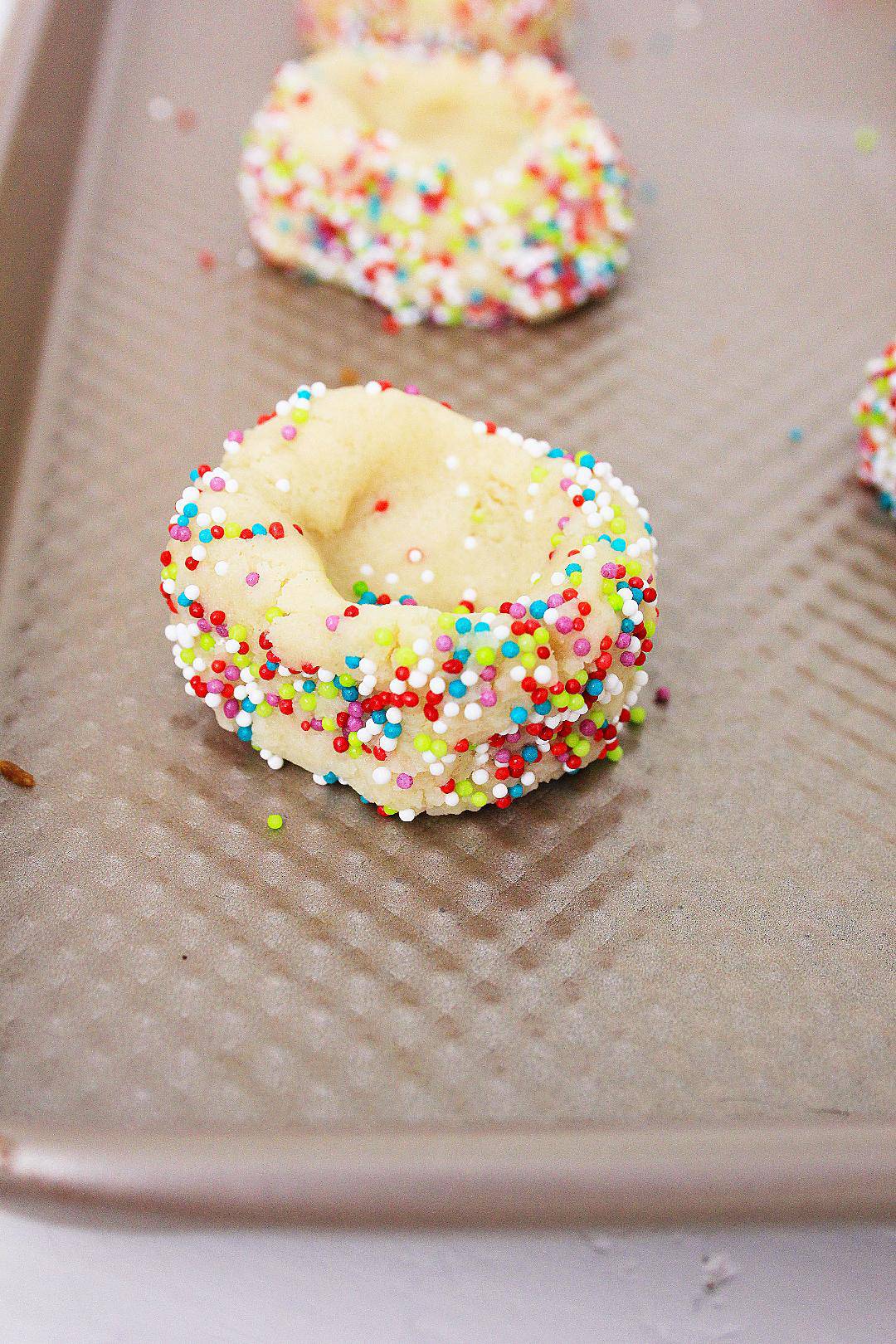 Thumbprint cookies with sprinkles on pan