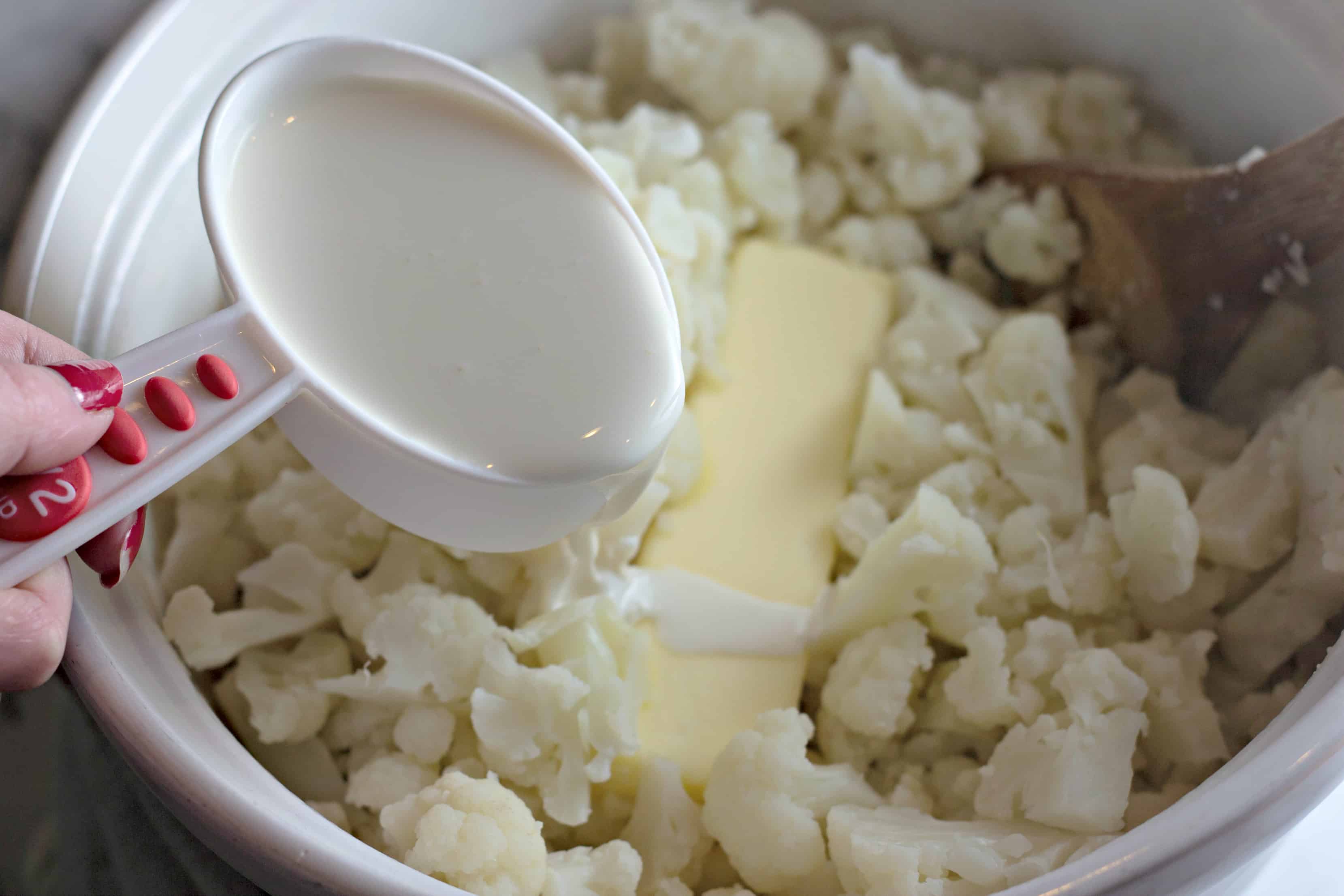 Steamed cauliflower in a white bowl with butter and cream