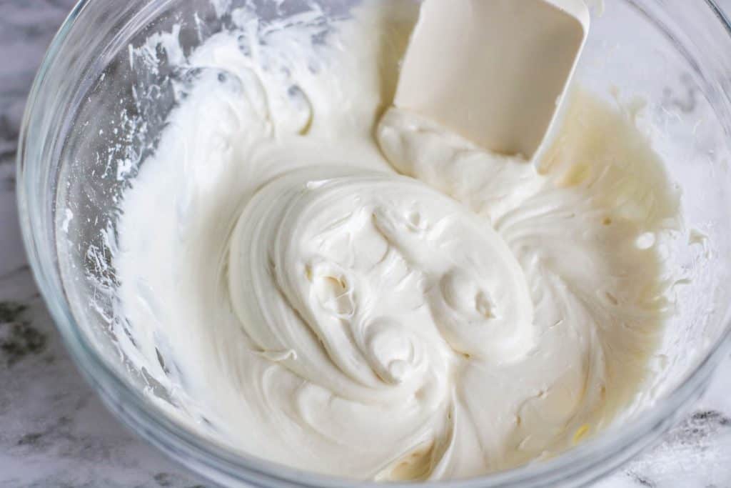 Cream cheese frosting in a bowl with a spatula.