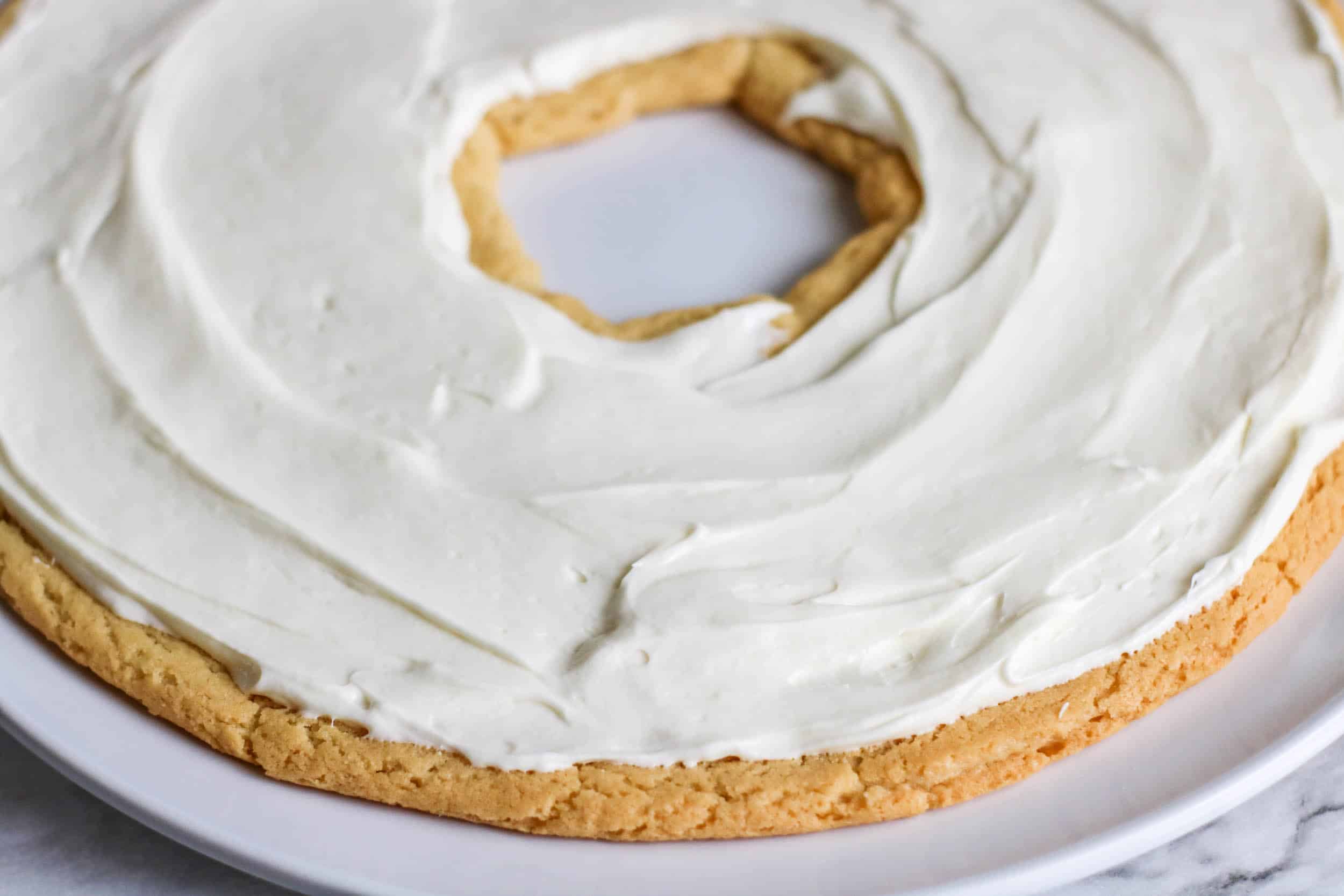 Cream cheese frosting spread on cookie wreath
