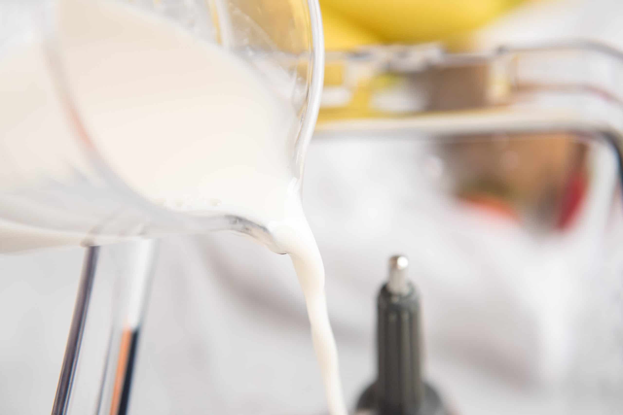Almond milk being poured into a blender.