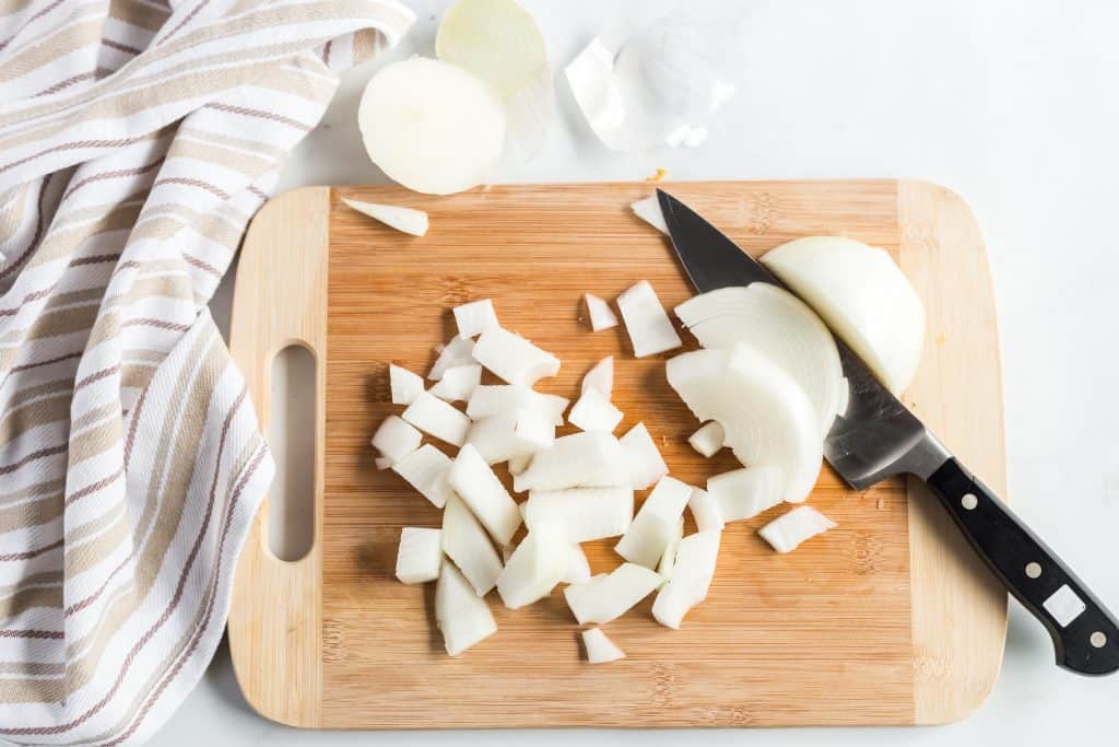 Diced white onion on a wood cutting board.