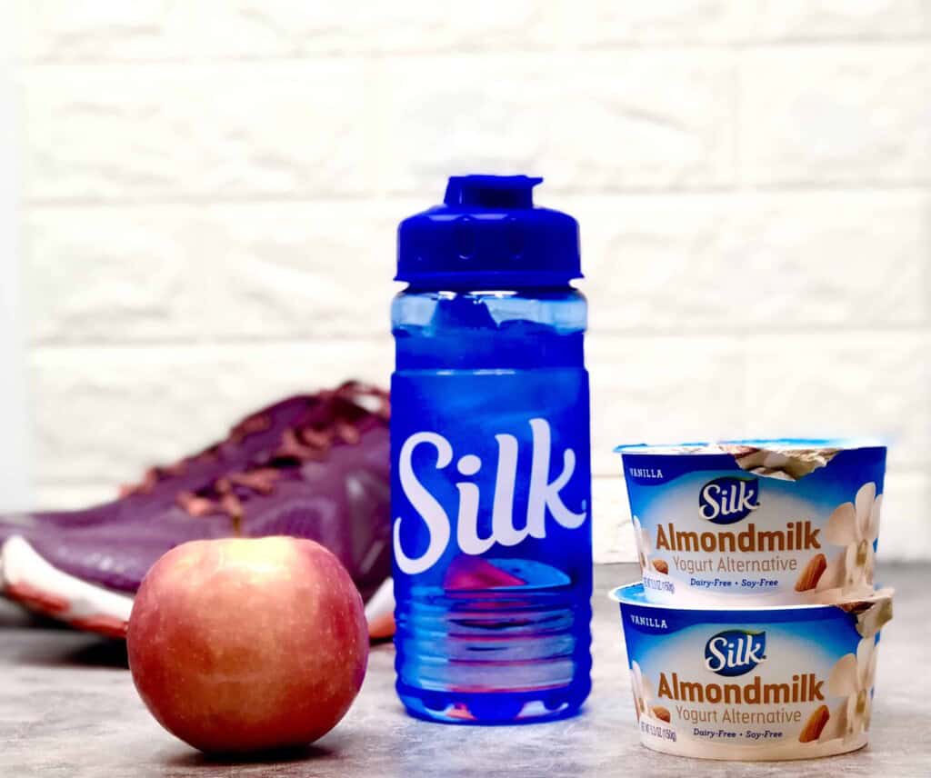 Apple, Silk water bottle, Almond milk yogurt and purple sneakers 