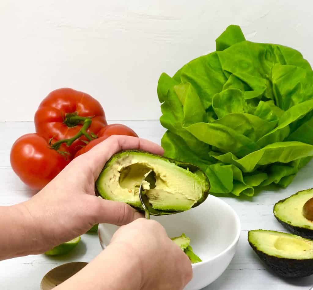 Scooping avocado into a bowl.
