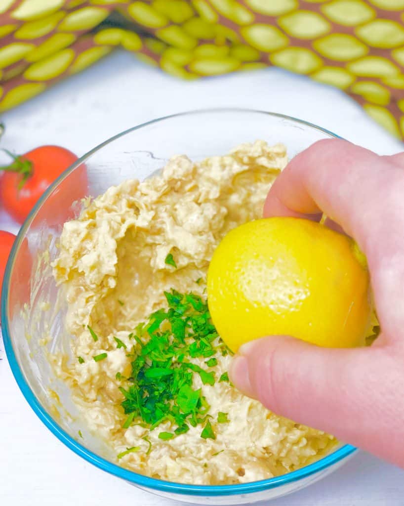 Squeezing fresh lemon juice into chicken salad with tarragon.