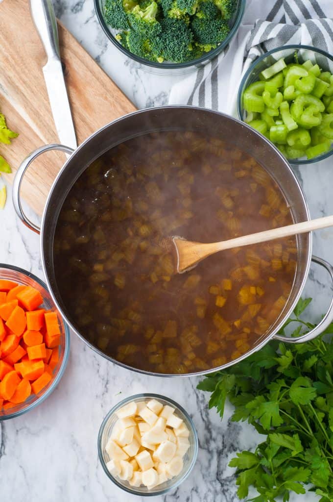 Vegetable stock and onions in a pot.