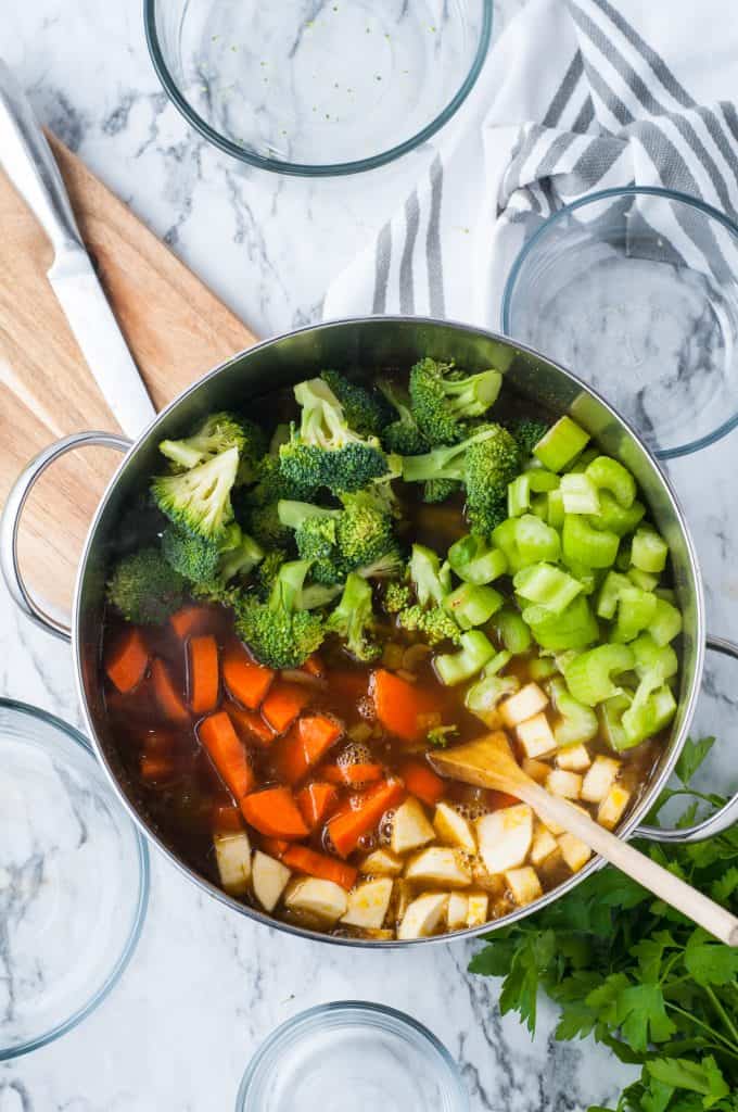 broccoli, carrots, celery, and parsnip in a pot with vegetable stock.