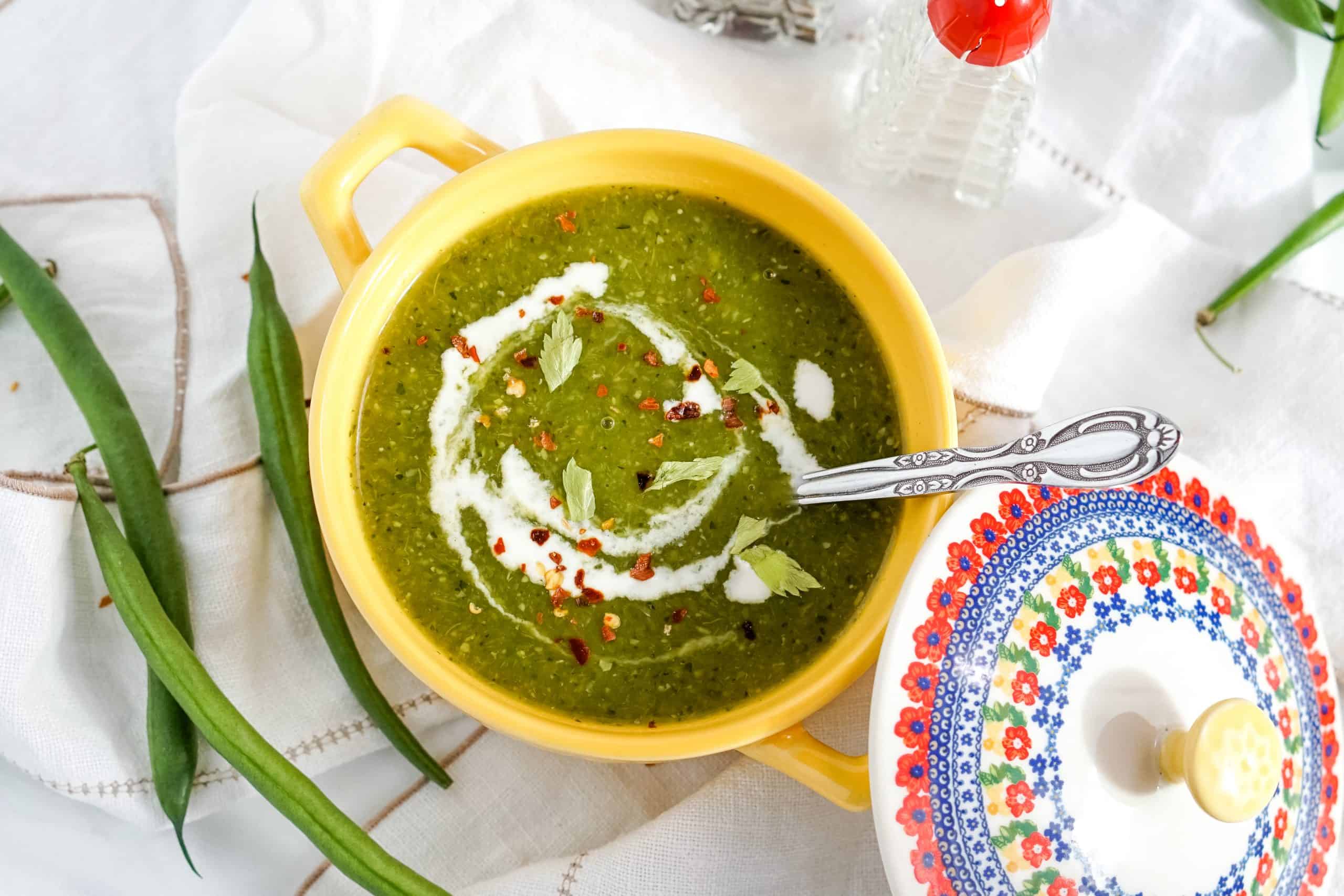 Green Detox Soup in a yellow pot on a white background.