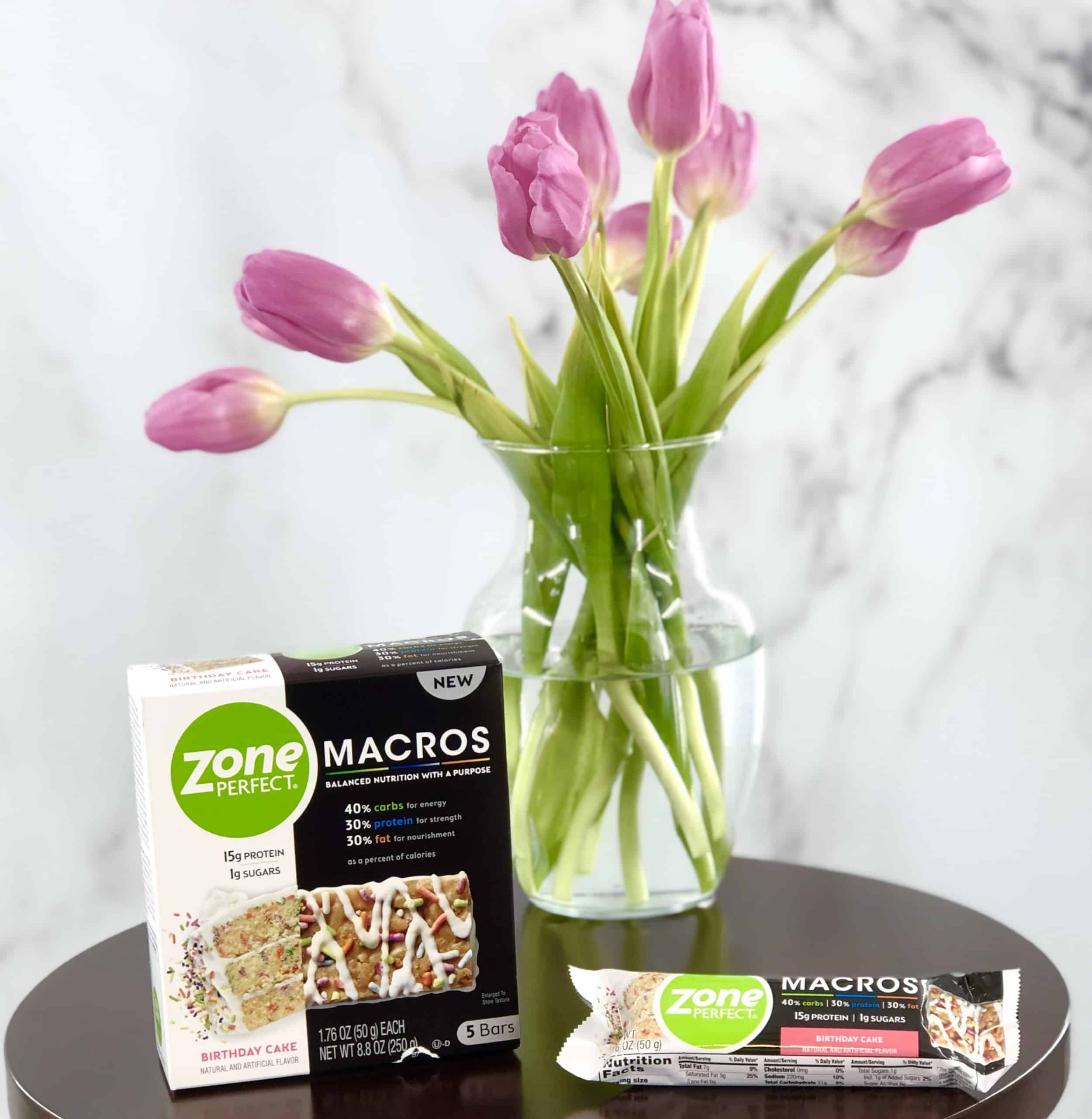 Zone Perfect Macro Bars on wood table with pink tulips in the background.
