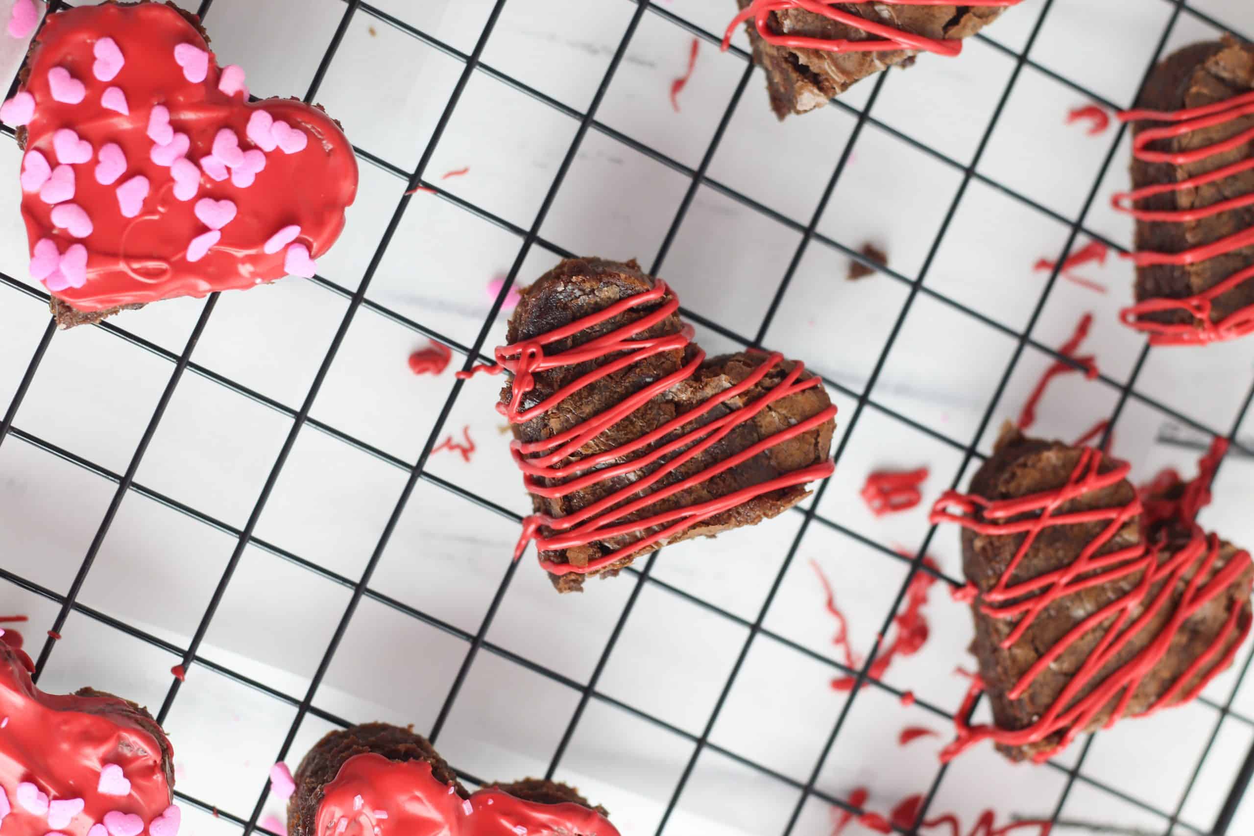 Decorated heart shaped brownies on a wire rack.