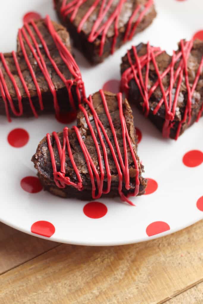 Overhead view of heart-shaped brownies with red icing drizzled on top.