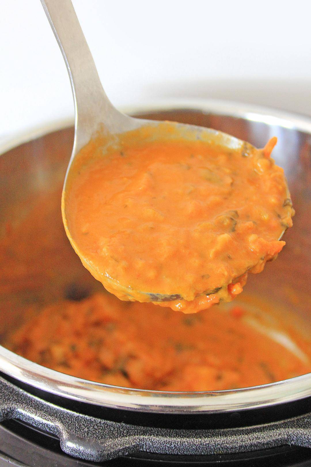 Creamy tomato sauce in ladle.