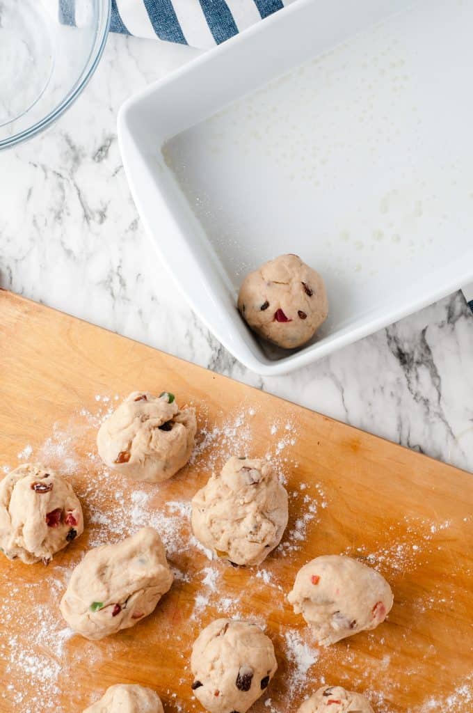 Hot cross bun dough being placed into a white ceramic baking dish.