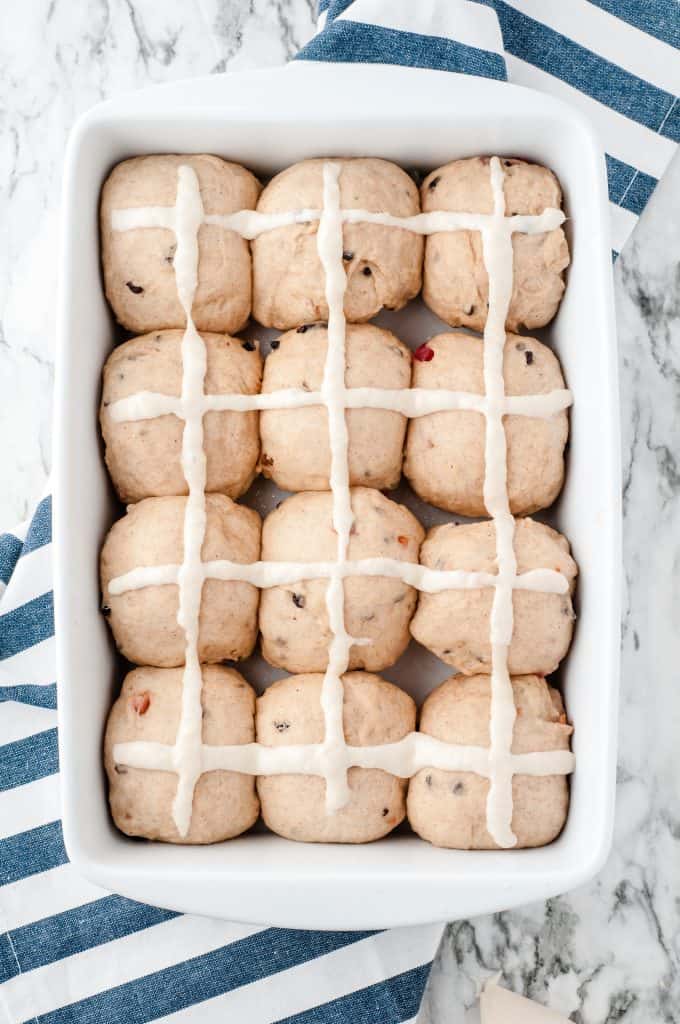 Hot cross buns in a white ceramic baking dish ready to go into the oven.