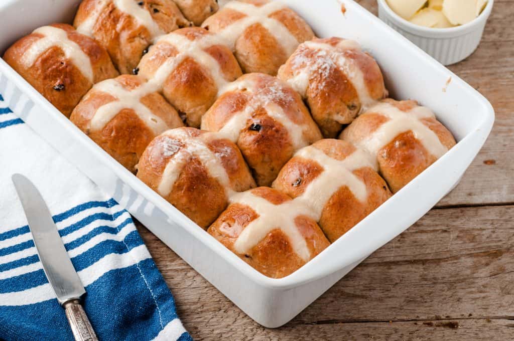 Old Fashion Hot Cross Buns in a white ceramic dish on a wood background.