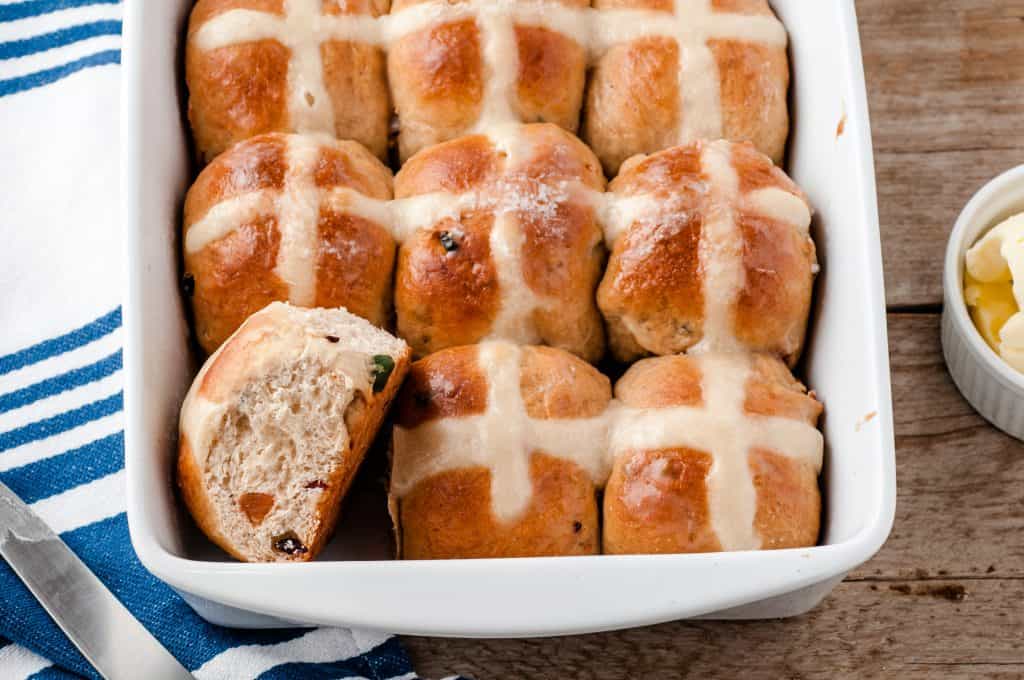 Hot cross buns in a white ceramic dish.