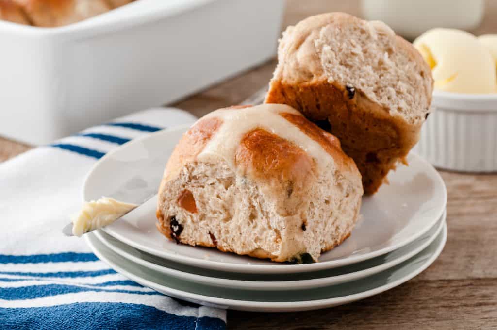 Sweet buns on white plates with butter in the background.