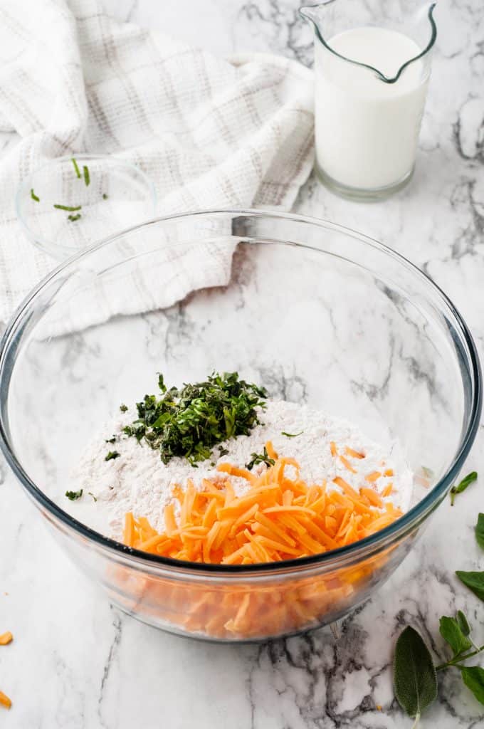 Glass bowl with cheese, flour and fresh herbs.